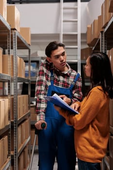 Warehouse manager teaching coworker managing order picking and fulfillment. Retail business storehouse asian man employee on crutches doing product quality control in storage room