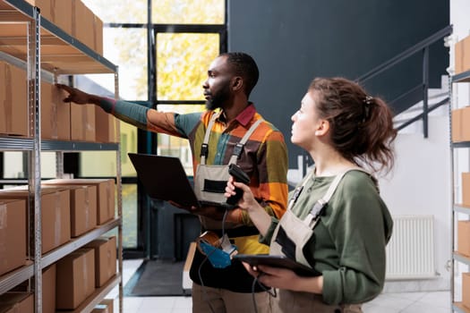 Diverse storehouse employees checking cardboard boxes, scanning products for inventory using store scanner in warehouse. Stockroom supervisors working at clients orders preparing packages for delivery