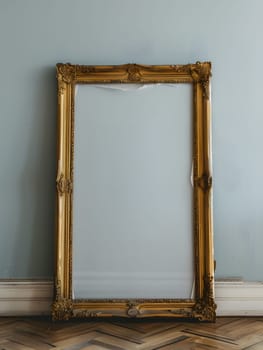 A rectangular gold picture frame rests against a wall on a hardwood floor, creating a still life photography scene showcasing tints and shades in visual arts