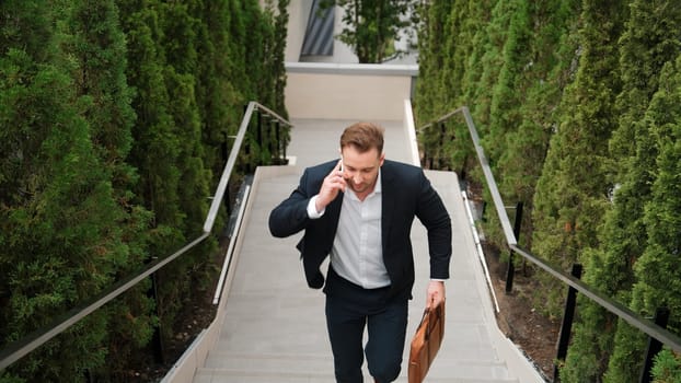 Caucasian businessman walking up stair and calling manager by using smart phone. Top view of manager talking marketing team and planning financial strategy by telephone while going up stair. Urbane.