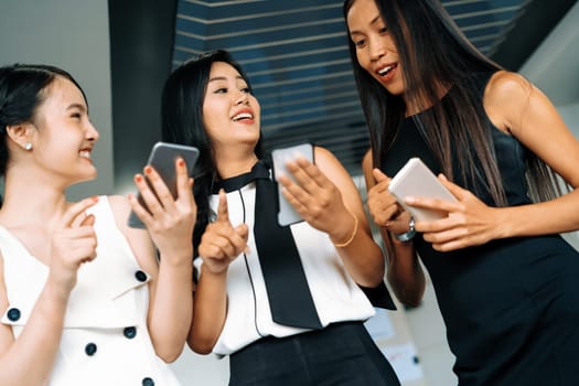 Three women friends having conversation while looking at mobile phone in their hands. Concept of social media, gossip news and online shopping. uds