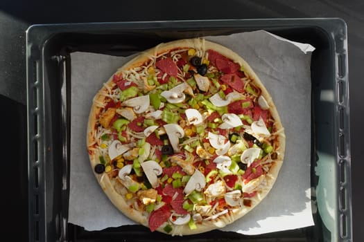 A loaded pizza on a pan with various toppings, a delicious fast food dish.