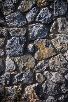 Stone wall texture. Decorative uneven cracked real stone wall surface.