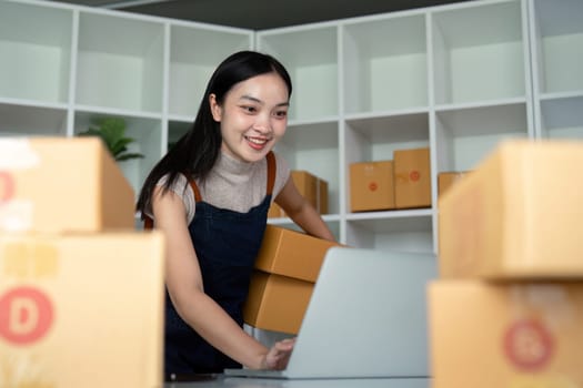 Woman asian in an online store check the customer address and package information on the laptop. Online shopping concept.