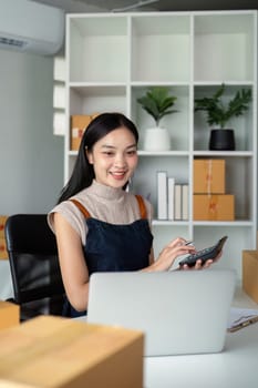 Young business woman asian working online ecommerce shopping at her shop. Young woman sell prepare parcel box of product for deliver to customer. Online selling.