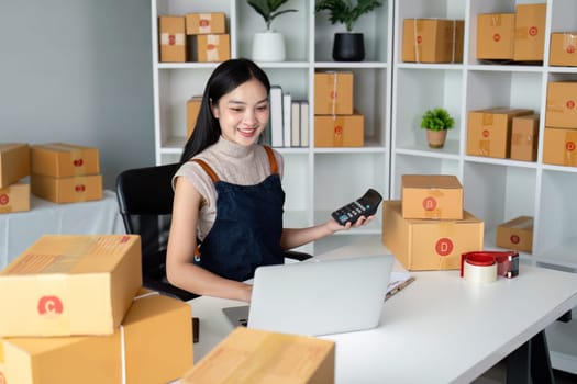 Young business woman asian working online ecommerce shopping at her shop. Young woman sell prepare parcel box of product for deliver to customer. Online selling.