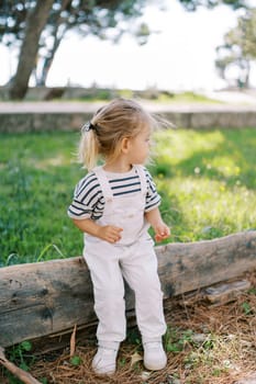 Little girl sits on a deck in the park and looks away. High quality photo
