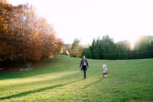 Mom and little girl are walking in the green meadow. High quality photo