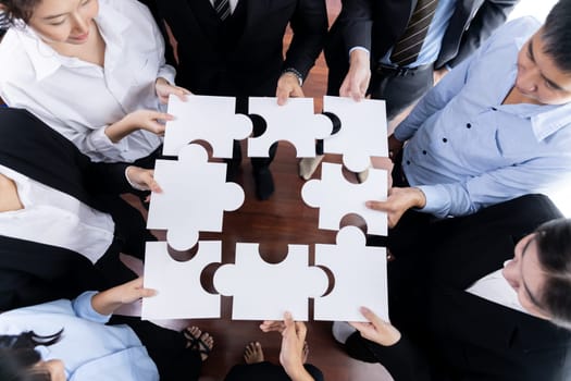 Top view multiethnic business people holding jigsaw pieces and merge them together as effective solution solving teamwork, shared vision and common goal combining diverse talent. Meticulous