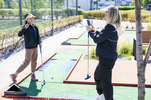 mother and daughter playing mini golf, children enjoying summer vacation. High quality photo