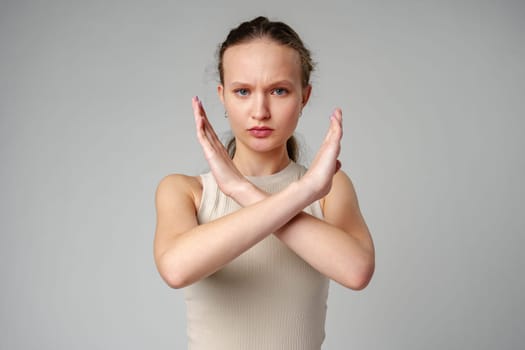 Young Woman Making Stop Sign With Hands on gray background in studio