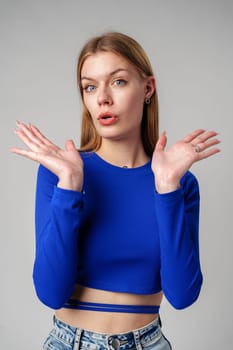 Young Woman in Blue Top Holding Out Hands in studio