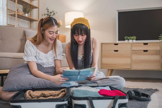 Two women are sitting on the floor looking at a map. She is planning to go on holiday..