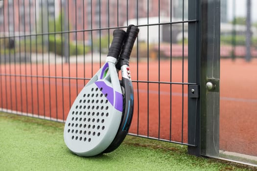 Padel racket and padel ball on a green court in the sunset. High quality photo