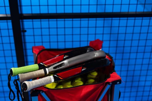 Black Paddle. Racket, balls an net in real court without logos. High quality photo