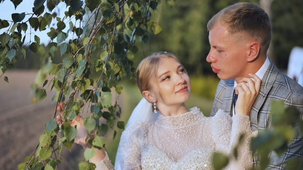 The bride and groom enjoy each other by the branches of a birch tree