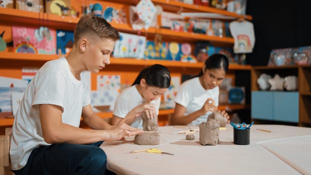 Group of happy smart diverse student working with clay art at pottery workshop. Multicultural attractive highschool student modeling, smash, playing clay. Creativity activity concept. Edification.