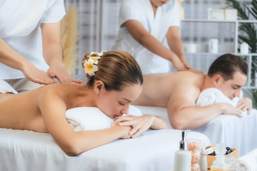 Caucasian couple customer enjoying relaxing anti-stress spa massage and pampering with beauty skin recreation leisure in day light ambient salon spa at luxury resort or hotel. Quiescent