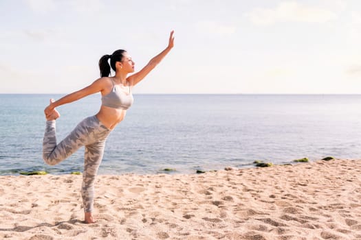 young asian woman in sportswear exercising on the beach with yoga poses, concept of mental relaxation and healthy lifestyle, copy space for text