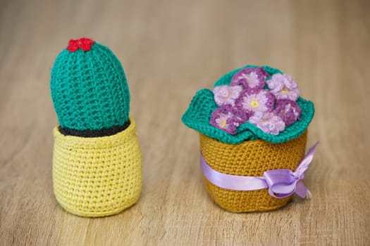 Knitted toys cactus and violet on the floor.