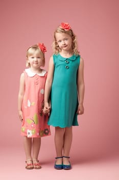 Portrait, studio background and siblings for fashion with development, vintage clothes and holding hands. Family, love and together with style inspiration by pink backdrop for kids with retro dress.