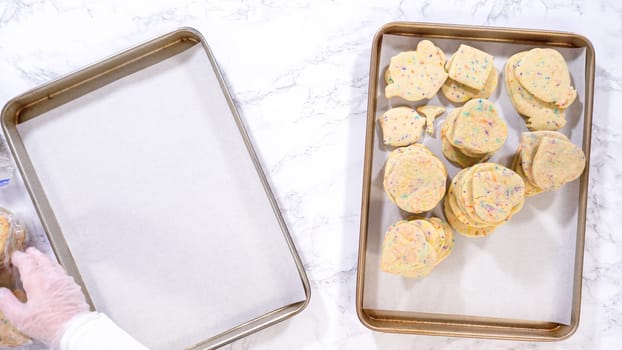 Flat lay. With precision, the woman is carefully arranging the sugar cookies, filled with dough-mixed sprinkles, into a rustic brown paper box.