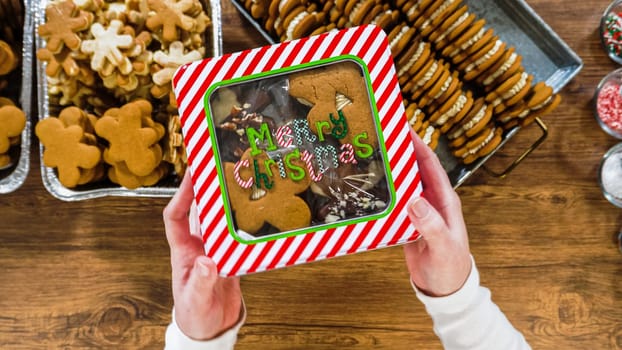 Flat lay. Lovingly homemade gingerbread and sugar cookies, half-dipped in rich chocolate, nestled in decorative Christmas tin boxes perfect for seasonal gifting.