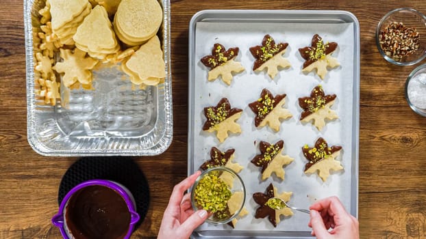 Flat lay. Creating snowflake-shaped cutout sugar cookies, dipped in chocolate, and adorned with different toppings.