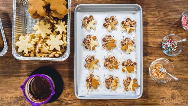 Flat lay. Creating snowflake-shaped cutout sugar cookies, dipped in chocolate, and adorned with different toppings.