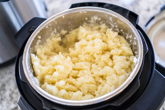 In a sleek modern kitchen, preparing velvety mashed potatoes using a pressure cooker for a quick and delicious meal.