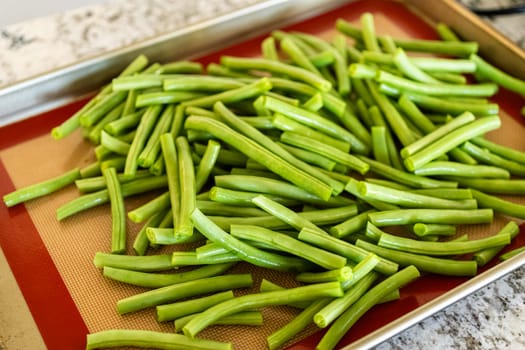Watch as fresh green beans are beautifully roasted to perfection on a baking sheet with a silicone mat, adding a burst of flavor to your meal.