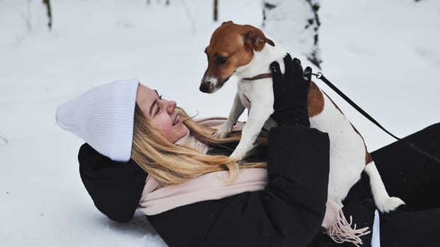 A girl playing with her Jack Russell Terrier dog in the snow