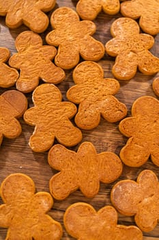 Making gingerbread man cookie sandwiches filled with eggnog buttercream, arrayed on a rustic wooden table, ideal for heartfelt Christmas gifting.