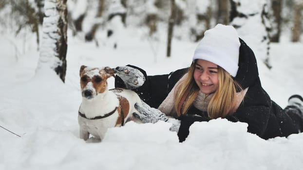 A girl playing with her Jack Russell Terrier dog in the snow