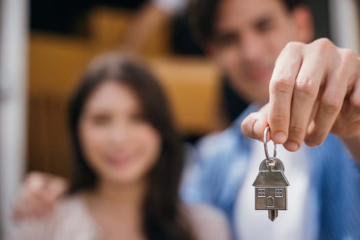 Couple happily shows keys carrying a mattress into their new home marking a successful relocation. Their happiness portrays the joy of moving. Moving Day Concept