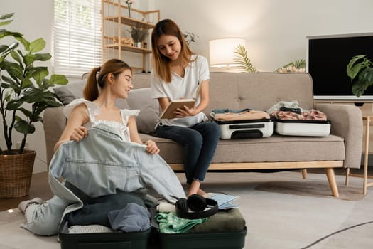 Two young female friends use a tablet to view travel information online for a vacation together. While packing your suitcase.