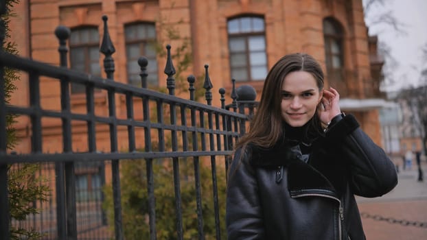 Happy brunette girl posing in black jacket in autumn in the city