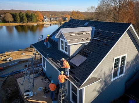 Aerial view of construction workers installing shingles on a roof of a new house by a lake