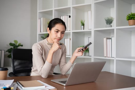 Asian businesswoman who is tired and has a headache from difficult work causing stress Sitting and looking at work at the desk in the office..