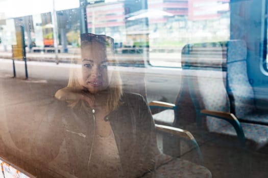 Woman traveler contemplating outdoor view from window of train. Young lady on commute travel to work sitting in bus or train