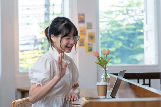 Asian students studying online talking together in an online chat meeting using laptops, studying online from home..