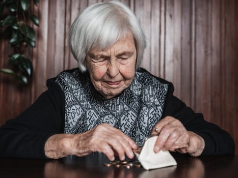 Portrait of an old woman counting money. The concept of old age, poverty, austerity