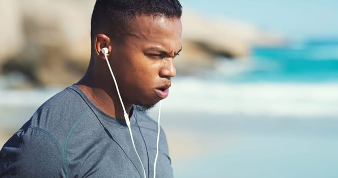 Fitness, headphones and black man with fatigue at beach to relax on audio, streaming and training. Workout, music and tired runner at ocean, listening to podcast and exercise challenge in nature.