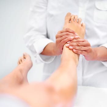 Client, woman and foot for massage at spa from therapist for treatment or pedicure with hands for health or skincare. Professional, therapy and zen with body care or healing for wellness at resort.