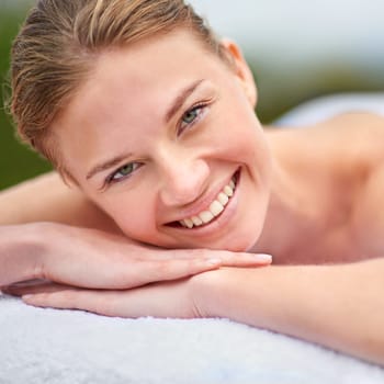 Spa, portrait and woman lying on massage bed for wellness, beauty treatment or body care. Smile, relax and happy person at luxury resort for stress relief, comfort or pamper on tropical holiday.