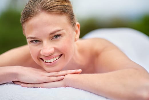 Portrait, massage and happy woman on bed for spa treatment, wellness or body care. Smile, relax and face of female person at luxury resort for stress relief, comfort or pamper on tropical holiday.