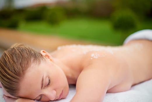 Woman, relax and table in spa with salt, therapy and self care for body wellness and resting for tension. Comfortable and resort with client, treatment and healing, exfoliate session and cosmetology.