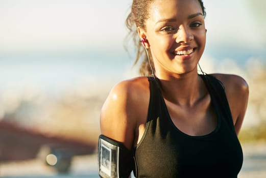 Woman, portrait and outdoor exercise with earphones or arm running strap for podcast, fitness app or workout. Female person, face and smile for music streaming in summer, subscription or playlist.