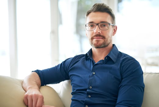 Businessman, glasses and portrait on sofa in airport for work, relax and out of town startup project. Male person, corporate and unwind on couch in waiting room for international, travel and company.