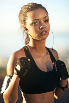 Woman, athlete or boxer in outdoor portrait for exercise, training and fitness with earphones. Female person, fists or fighter workout in nature with music playing for endurance, sports or cardio.